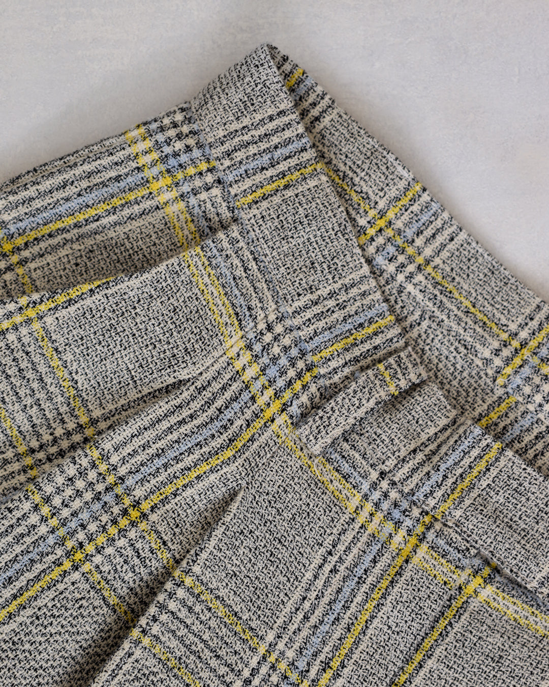 Flat lay of Juana Plaid Theory High Rise Trousers showing plaid pattern and sustainable fabric texture.