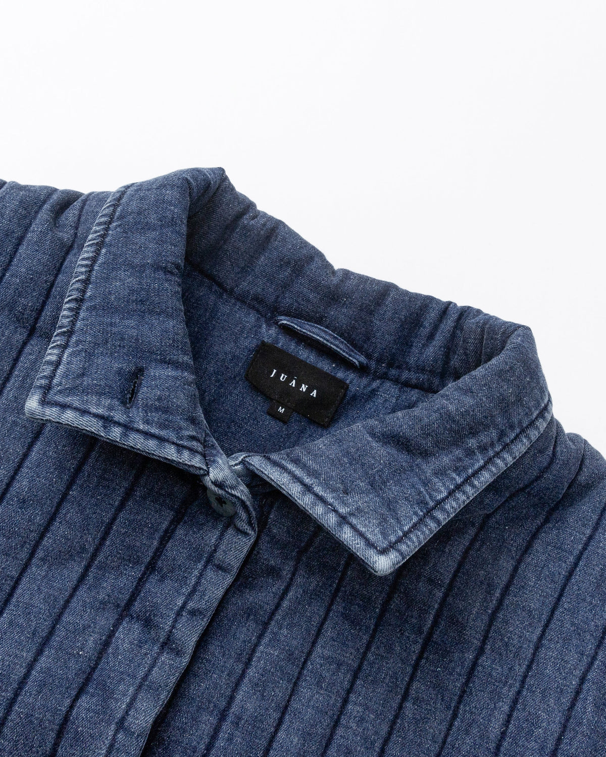 Juana Quilted Denim Jacket in Indigo Wash (organic cotton–hemp) layflat detail showing coconut buttons, quilting and front pocket construction.