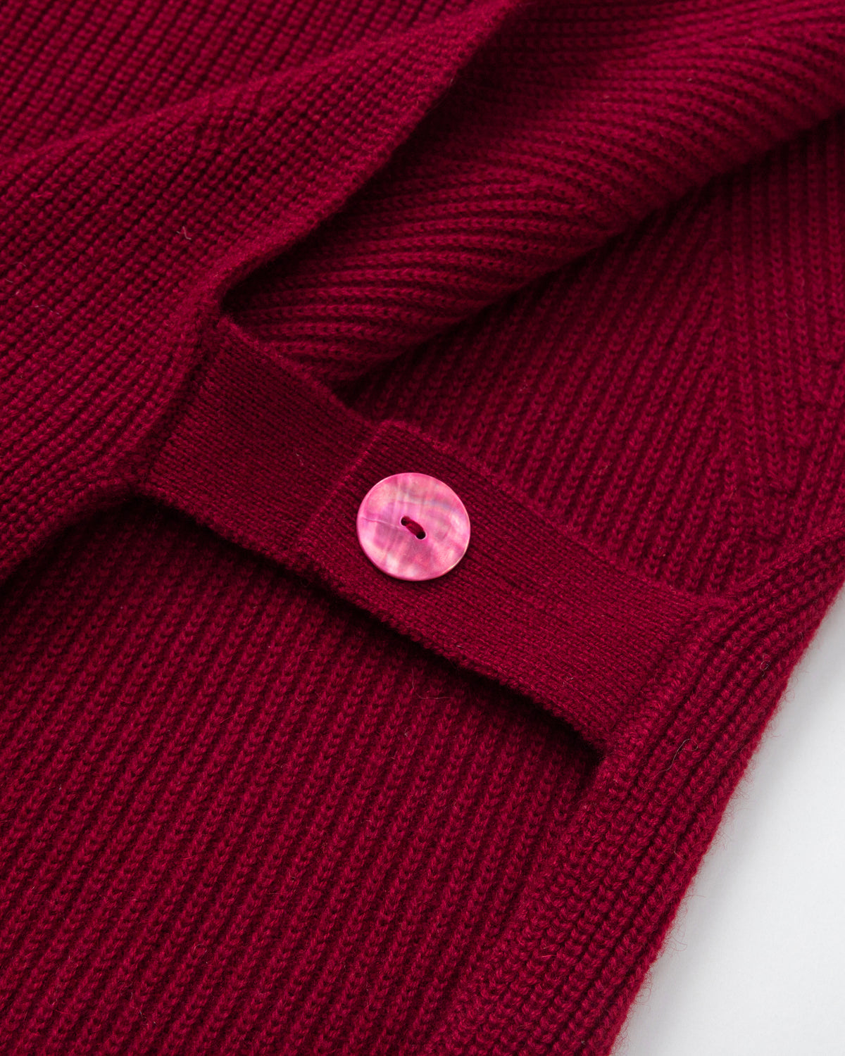 Juana Wool Cashmere Sweater Vest in Pomegranate (wool–cashmere) shown in a detail layflat with adjustable abalone shell side straps.