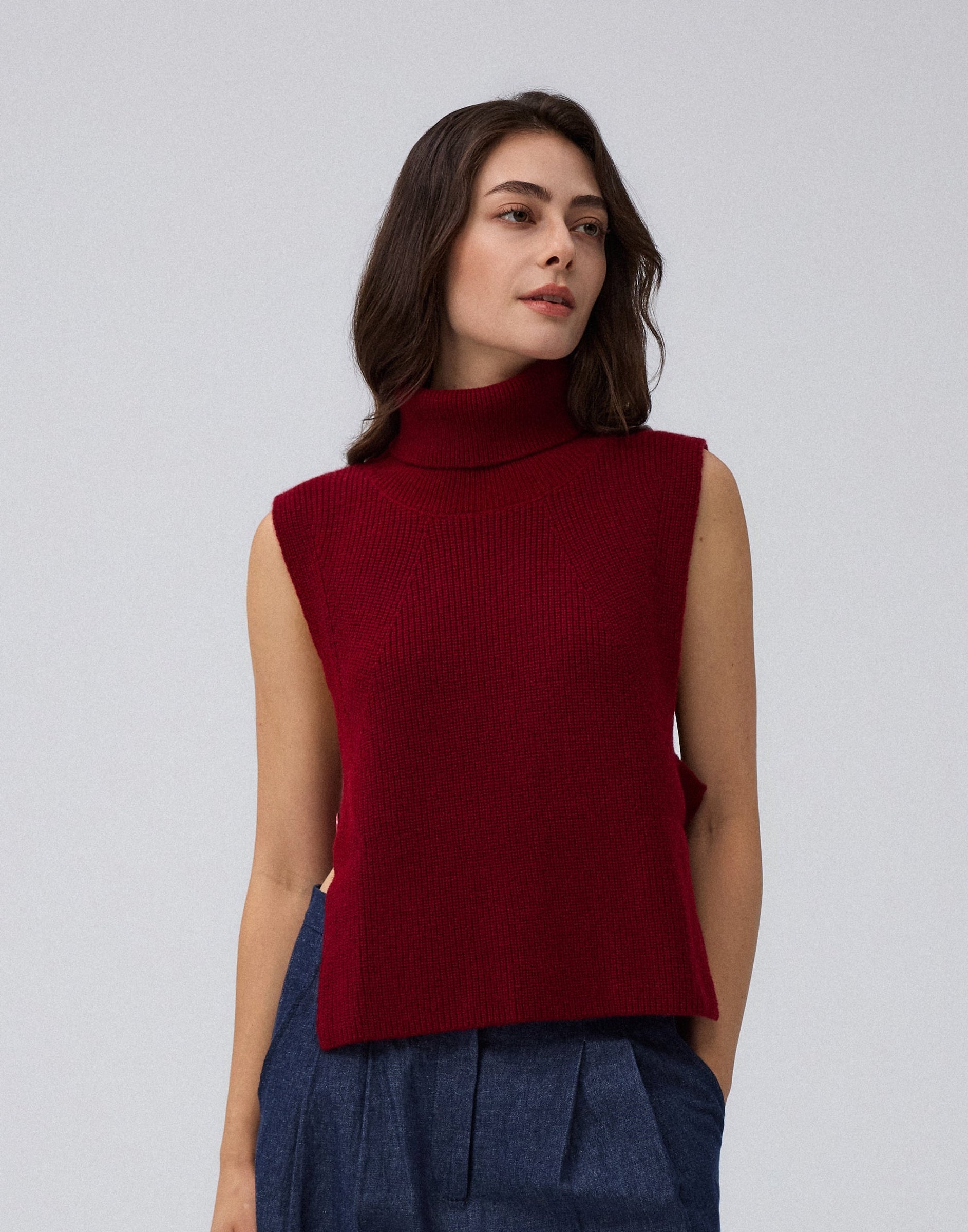 Juana Wool Cashmere Sweater Vest in Pomegranate (wool–cashmere) worn on a model in a front view with the open-side silhouette visible.