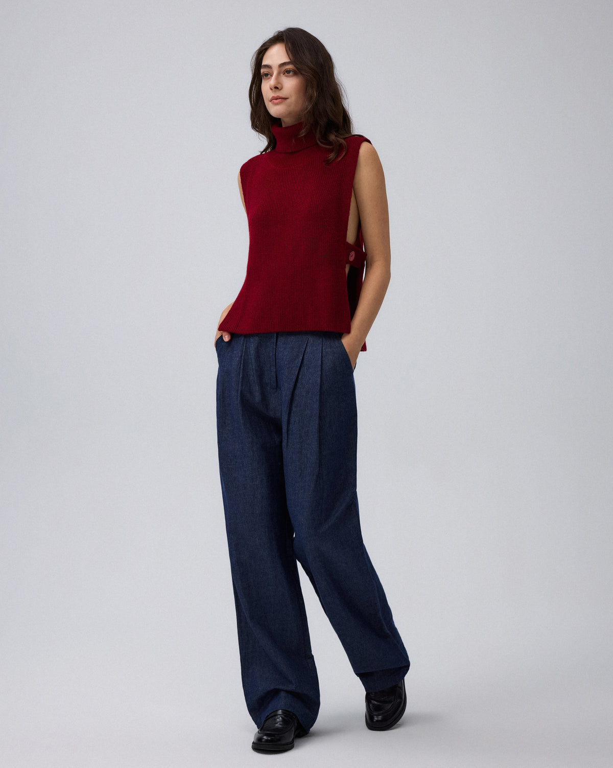 Juana Wool Cashmere Sweater Vest in Pomegranate (wool–cashmere) worn in a side view showing the open side and adjustable strap.