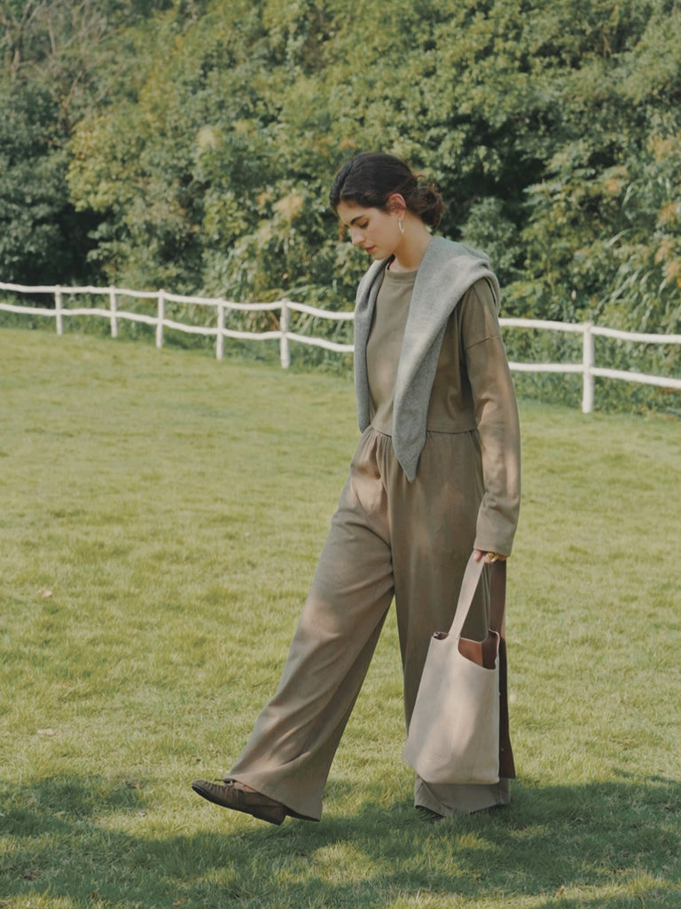 Model walking in a field wearing Juana Aera Boxy Sweater olive and Aera Pull-on Pants olive (hemp–organic cotton blend), showing relaxed, breathable drape.